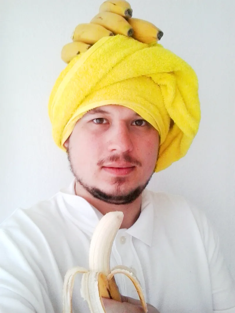 Konrad in a banana-print turban holding a banana