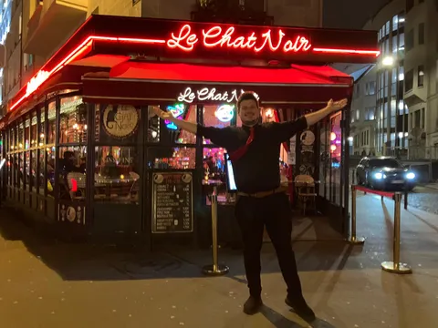 Konrad outside the neon front of Le Chat Noir